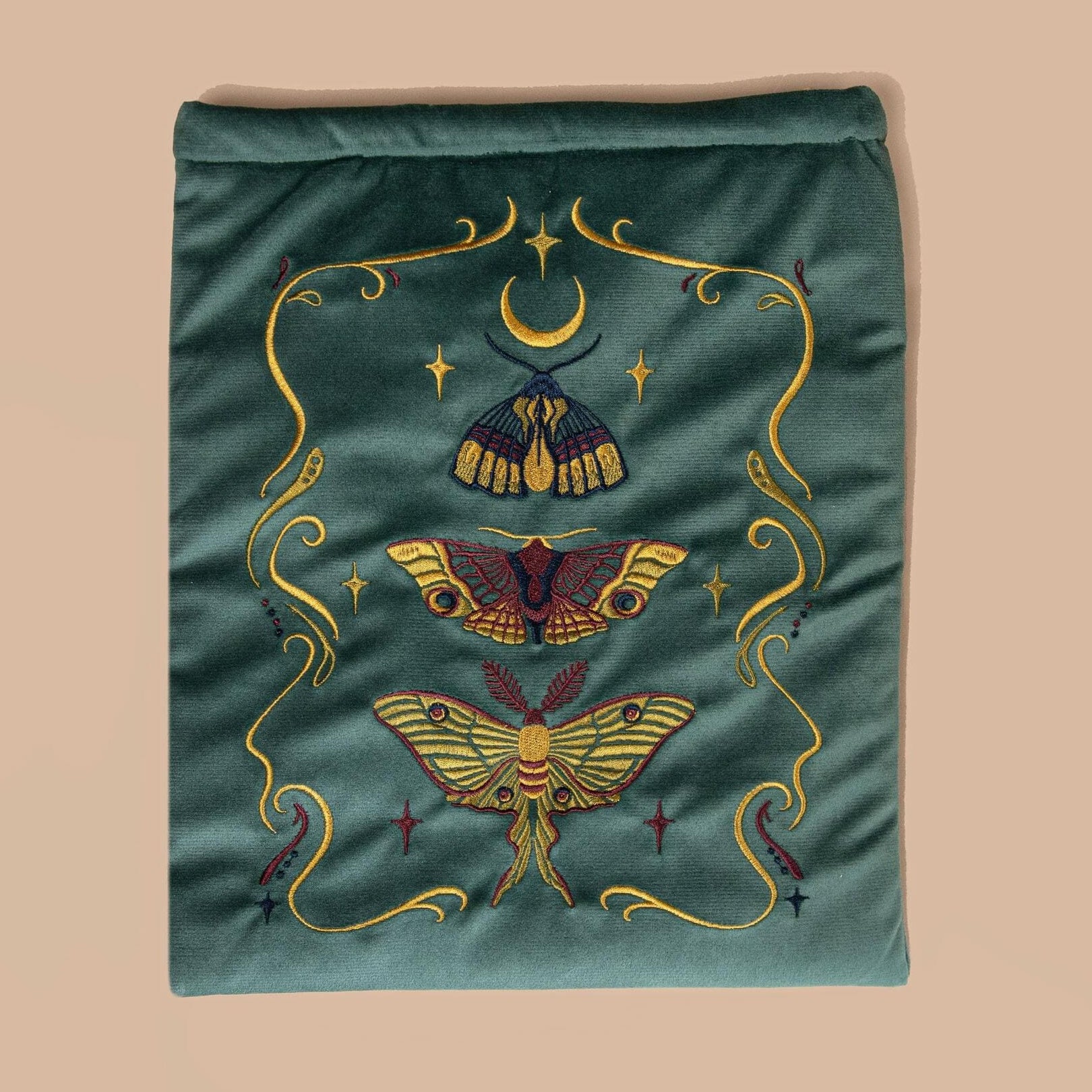 Embroidered velvet fabric with lunar moth designs on a teal background