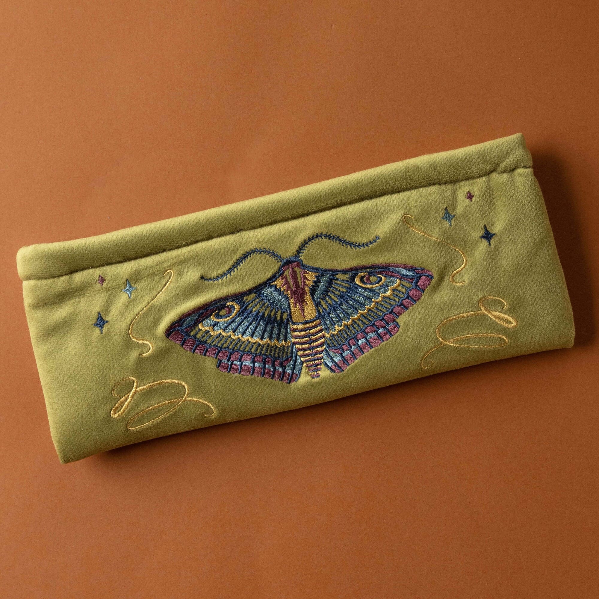 Embroidered pouch with a moth design on a brown background